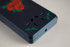 Close-up of a navy FswStudio Rose bassoon reed case showing the painted roses and engraved ventilation holes