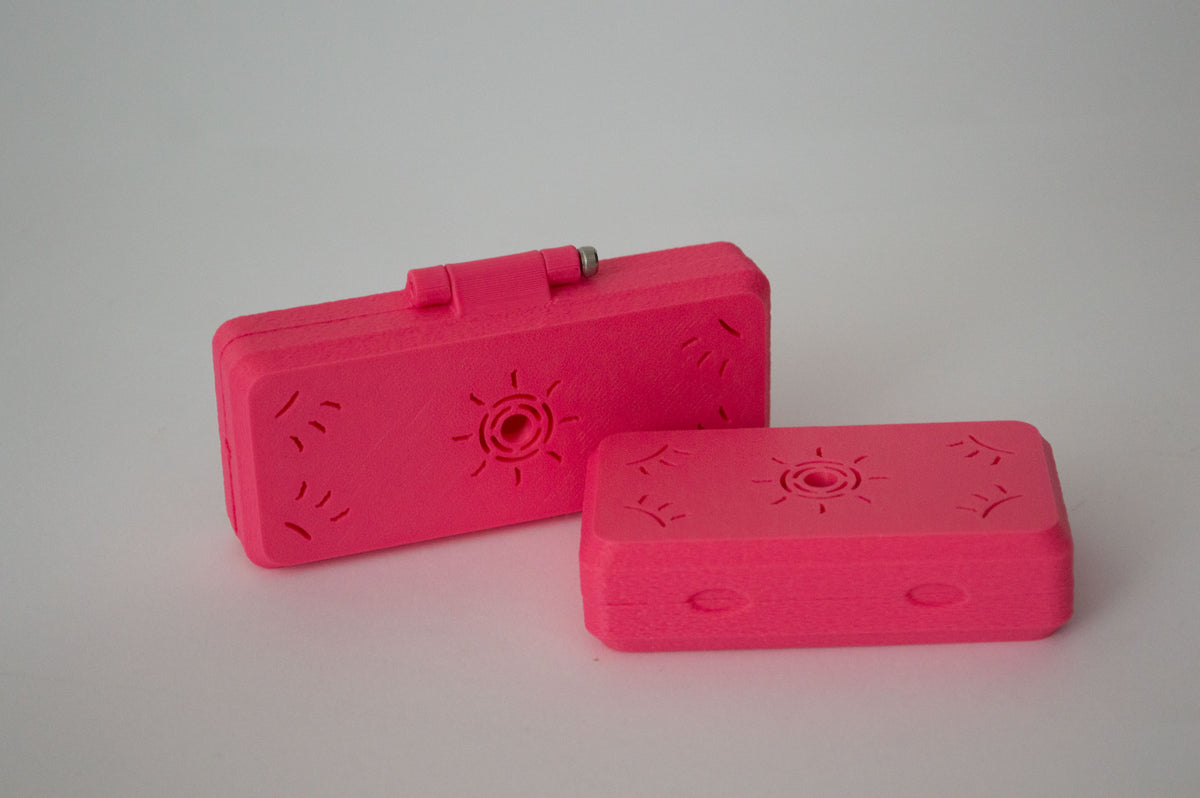Deux étuis à anches de basson imprimés en 3D rose vif, avec gravure soleil, illustrant l'option de couleur.