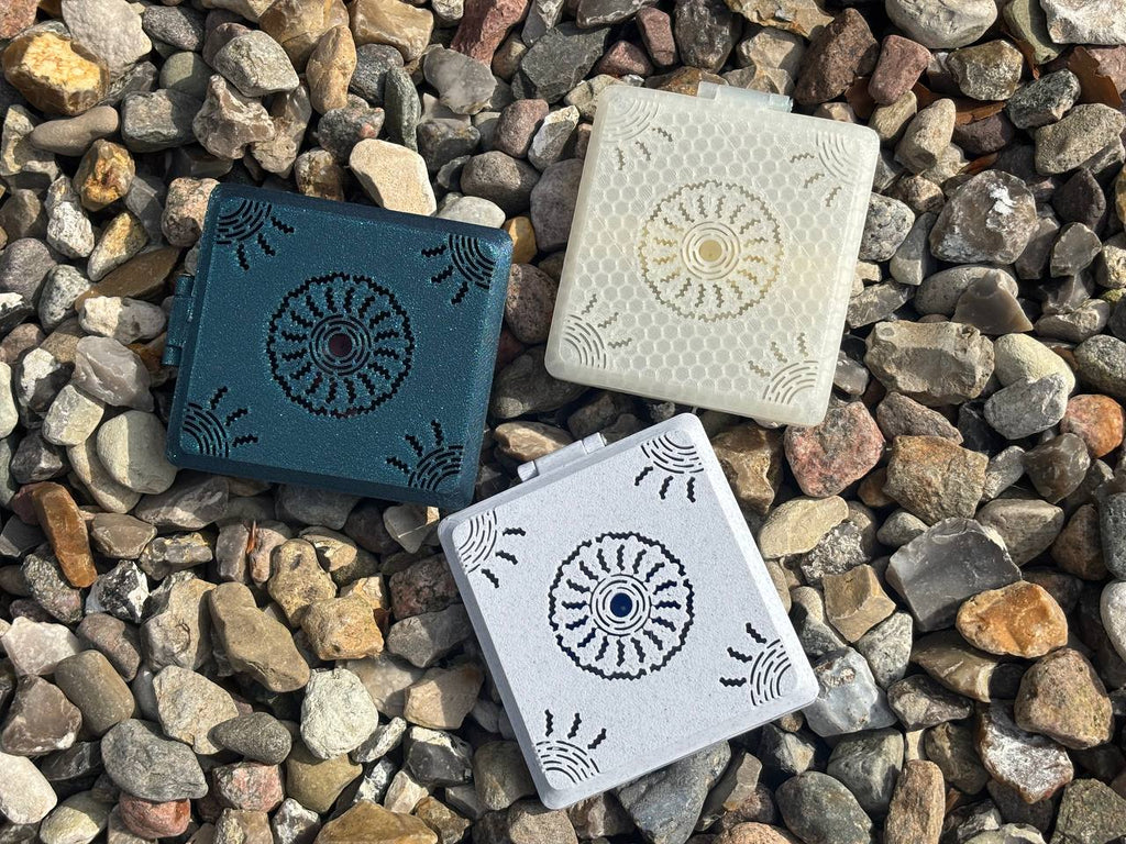 Three Combined Reed Cases by FswStudio, in dark green, off-white, and light gray, each hold 5 oboe and 3 English horn reeds. They feature decorative circular patterns and are shown on multicolored rocks.